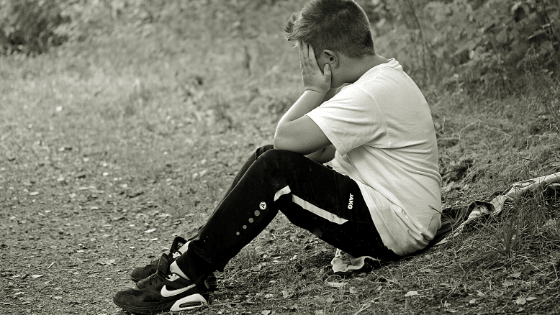 A young boy covering his face with two hands