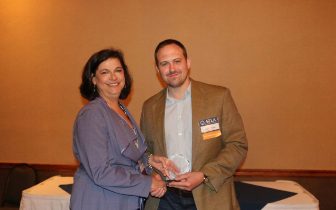 Josh Gillispie, Atla’s 2017 Outstanding Member – Young Lawyer Division wearing corporate attire and shaking hands with a professional woman